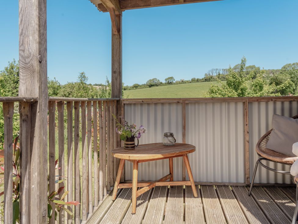 A balcony with a table and chair at Spindleberry Hut in Piddletrenthide