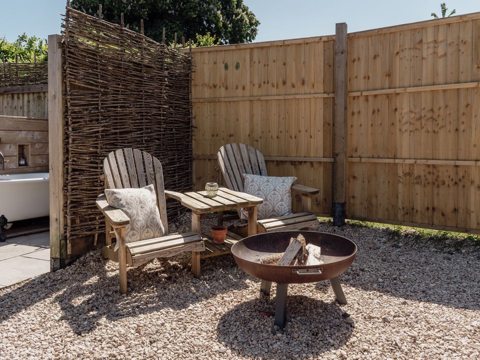 An outdoor seating area with chairs and a fire pit at Spindleberry Hut in Piddletrenthide
