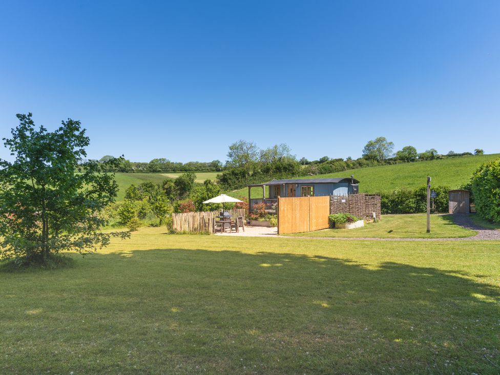 A garden with a fence and seating area at Spindleberry Hut in Piddletrenthide