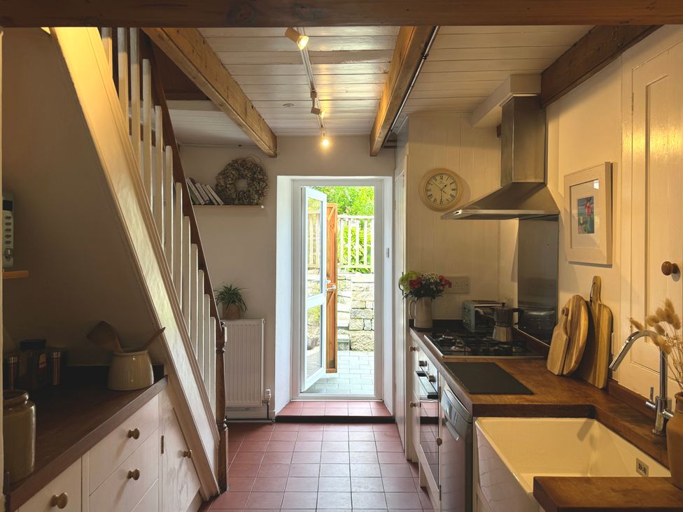 A kitchen with wooden countertops a gas stove sink and an open door leading outside at Bodillys Cottage in Newlyn