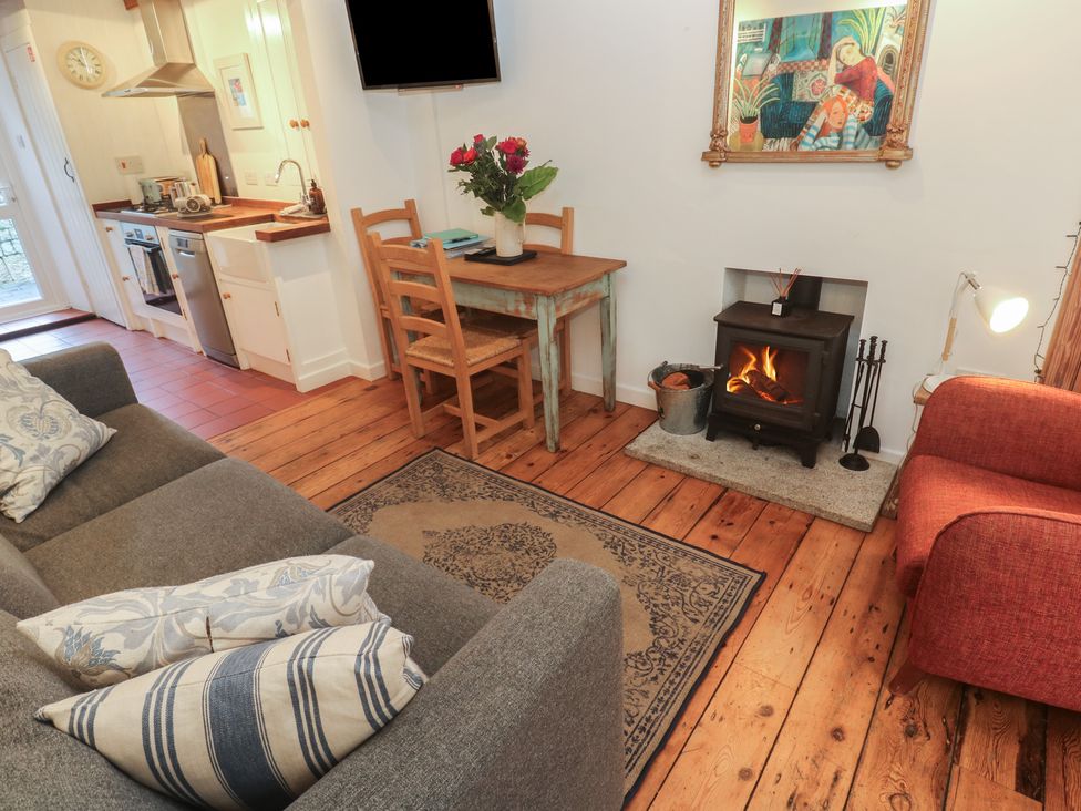 A living room with a sofa dining table and stove at Bodillys Cottage Newlyn