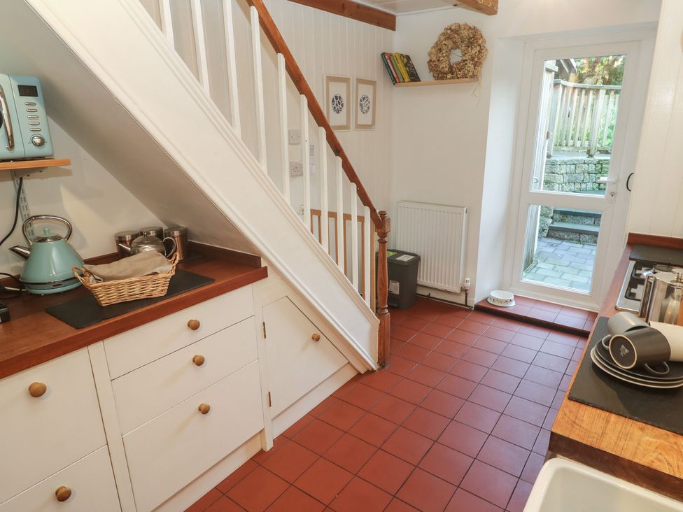 A kitchen with cabinets and a doorway to an outdoor area at Bodillys Cottage Newlyn