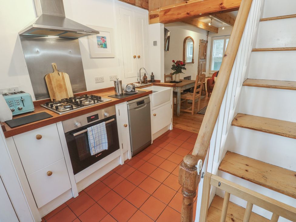 A kitchen with appliances and dining area at Bodillys Cottage Newlyn