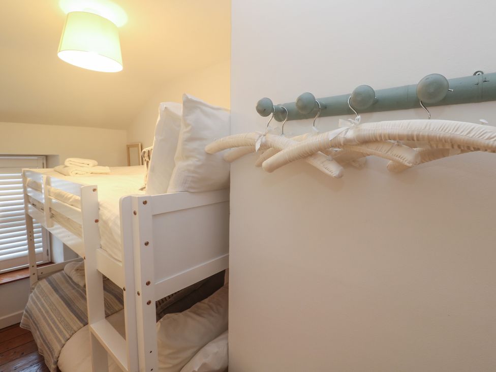 A bunk bed with bedding and a wall hanger at Bodillys Cottage Newlyn