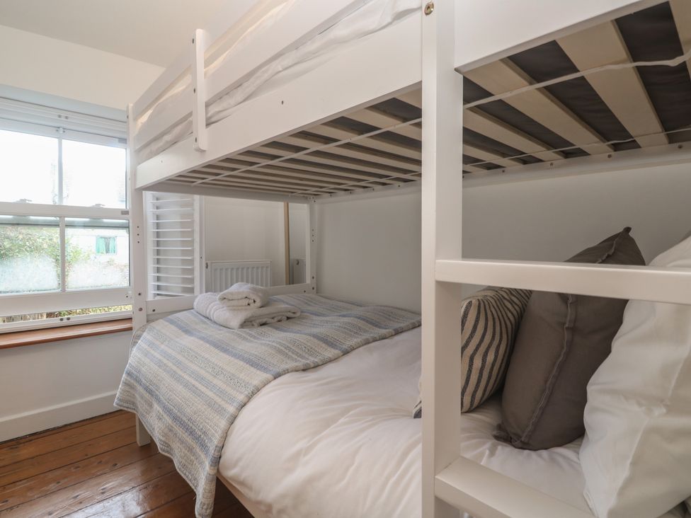 A bunk bed with linens and pillows at Bodillys Cottage Newlyn