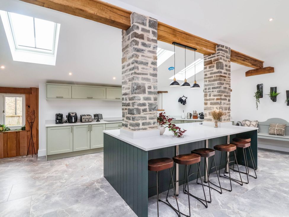A kitchen with a stone wall and bar stools at The Granary in Barnstaple