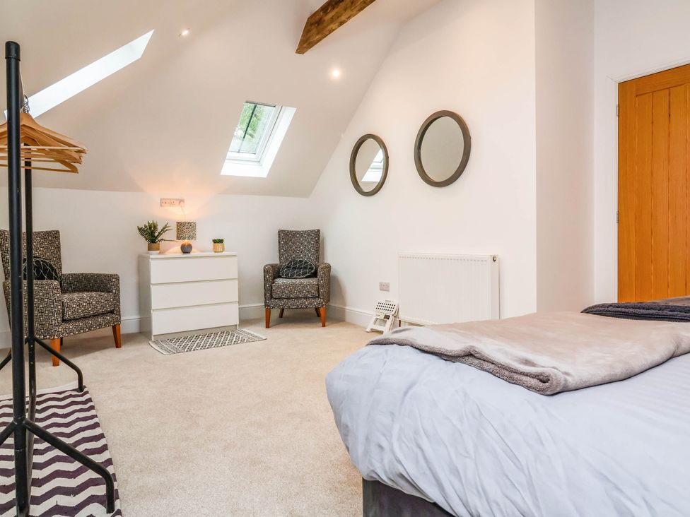 A bedroom with a bed, chairs, and a wardrobe at The Granary in Barnstaple