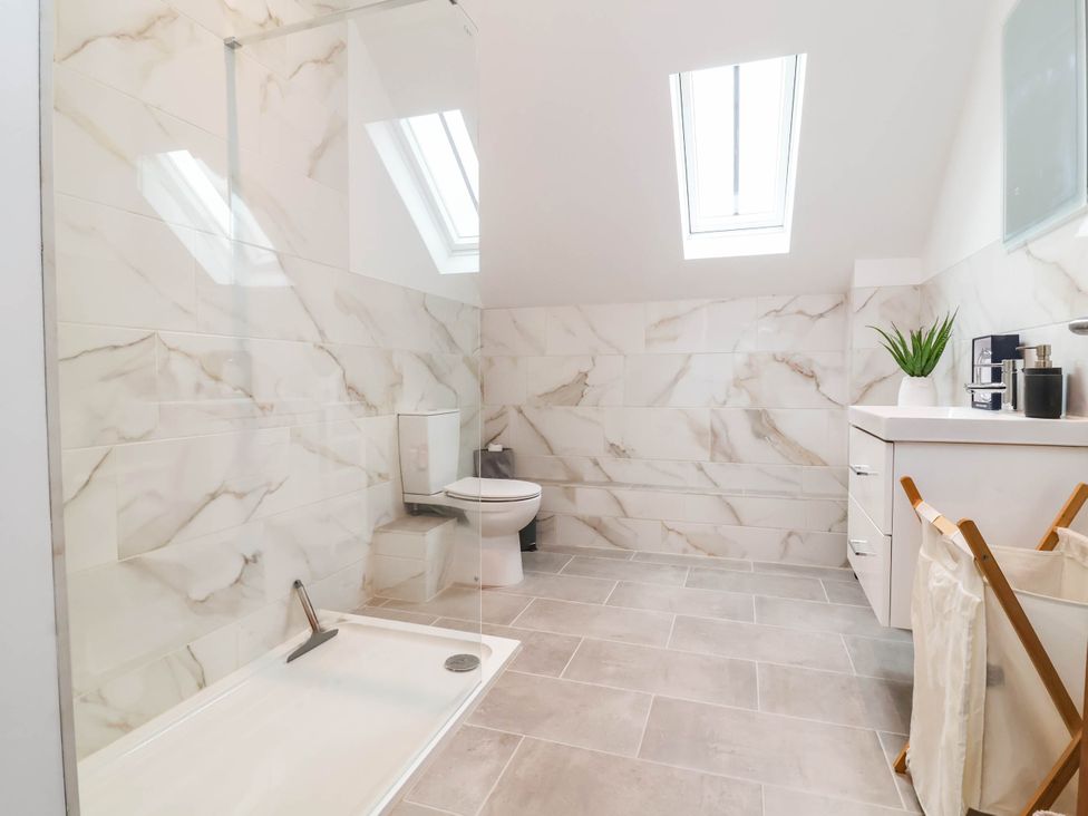 A bathroom with shower, toilet, sink and shelves at The Granary in Barnstaple