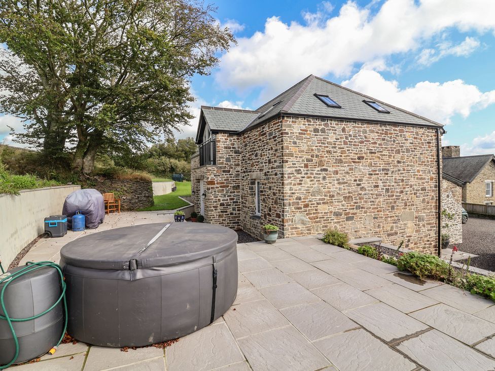 An outdoor area with a hot tub and stone wall at The Granary in Chelfham near Barnstaple