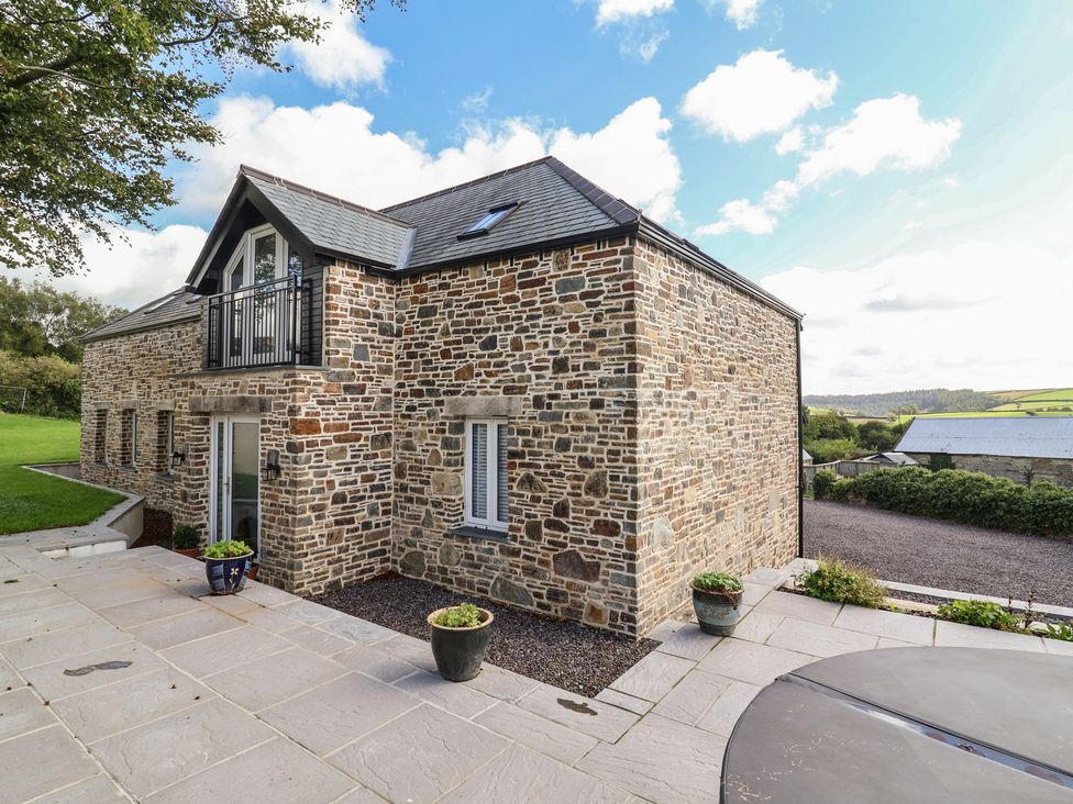 A stone house with a balcony and garden area at The Granary in Chelfham near Barnstaple