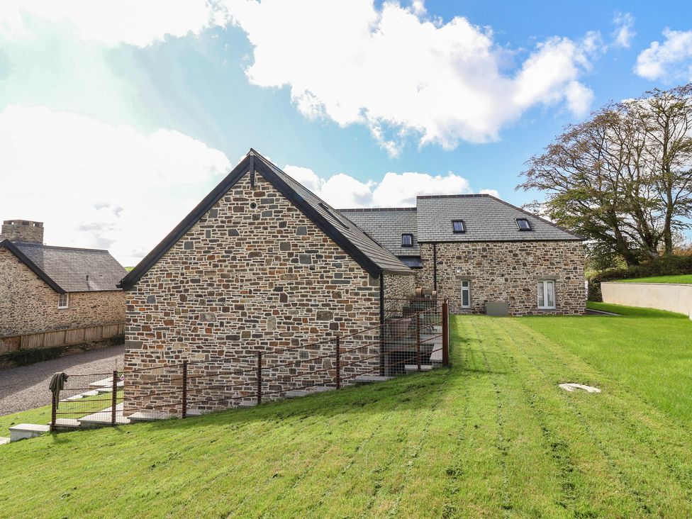 A stone house with grass and a fence at The Granary in Chelfham near Barnstaple