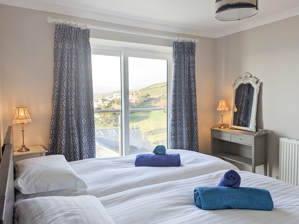 A bedroom with two beds and a mirror at Looe Island View in Downderry