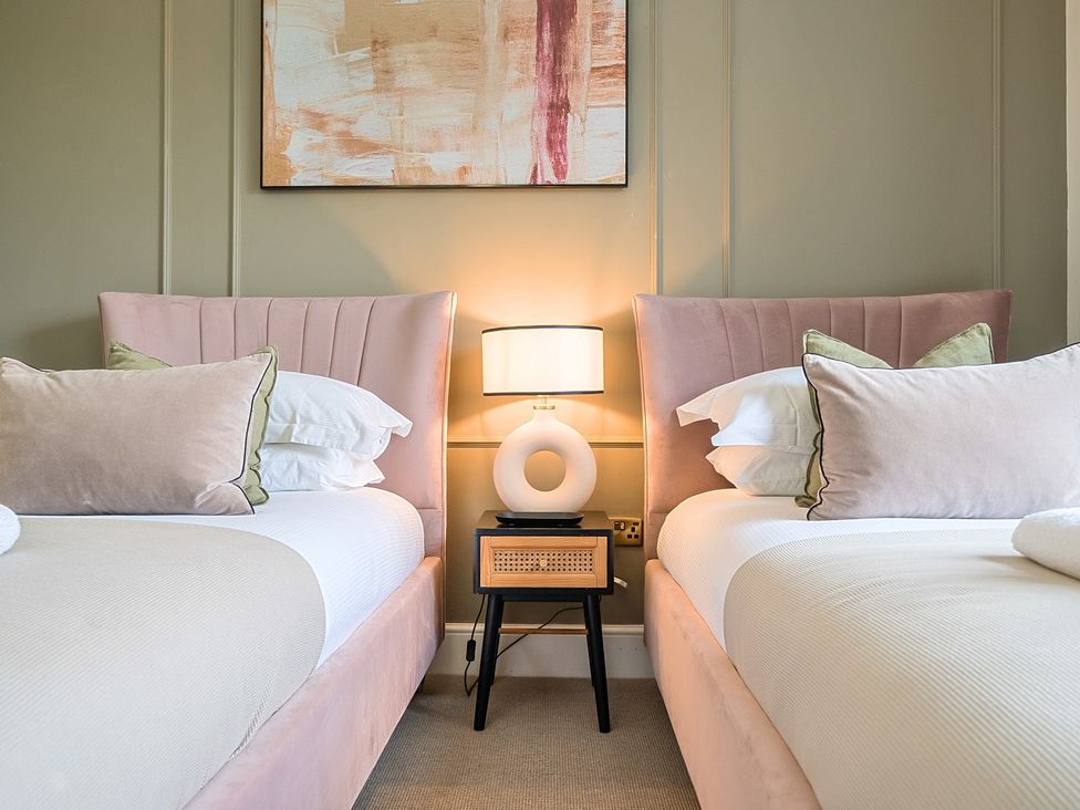 A bedroom with two beds and a lamp on a table at Hillside House Aysgarth near West Witton