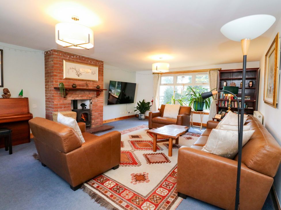 A living room with a sofa, coffee table, and piano at Ninevah, Balquhidder, Perthshire, Scotland