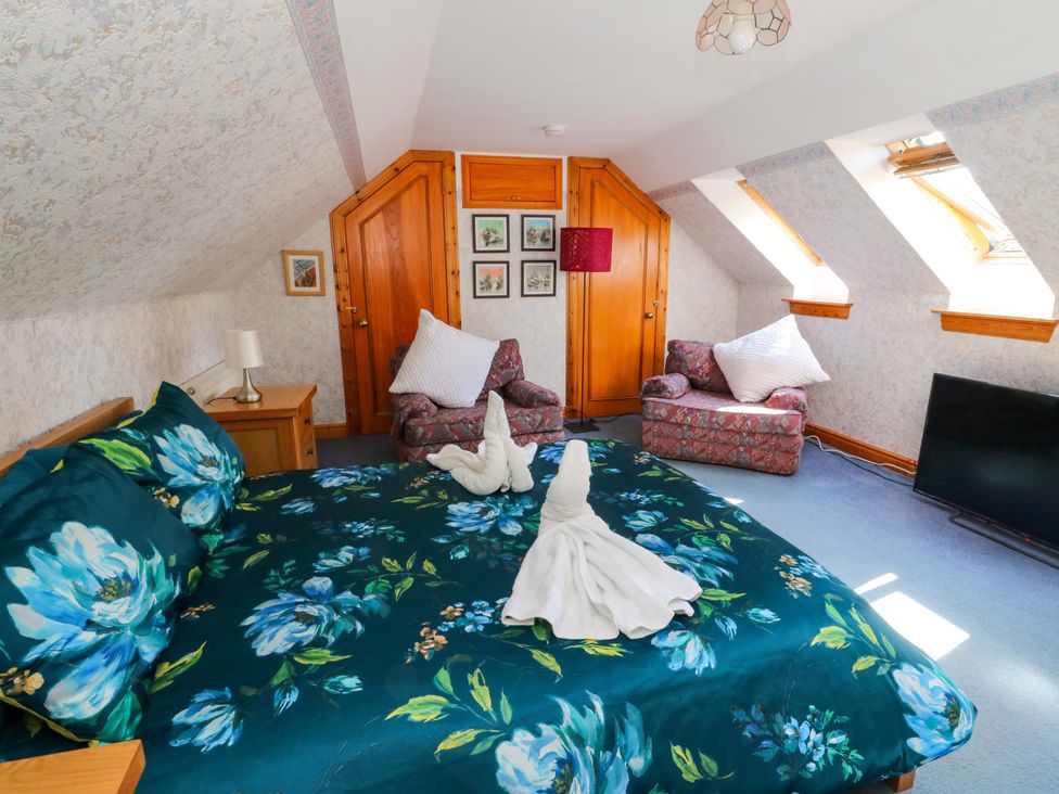 A bedroom with a bed and seating area at Ninevah in Balquhidder, Perthshire, Scotland
