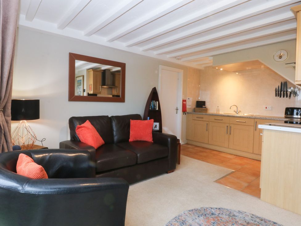 A living room with a sofa and kitchen area at Oak Cottage in Dinas Dinlle near Caernarfon