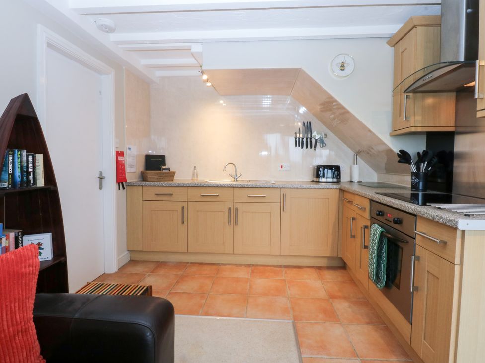 A kitchen with cabinetry, sink, and stove at Oak Cottage Dinas Dinlle near Caernarfon