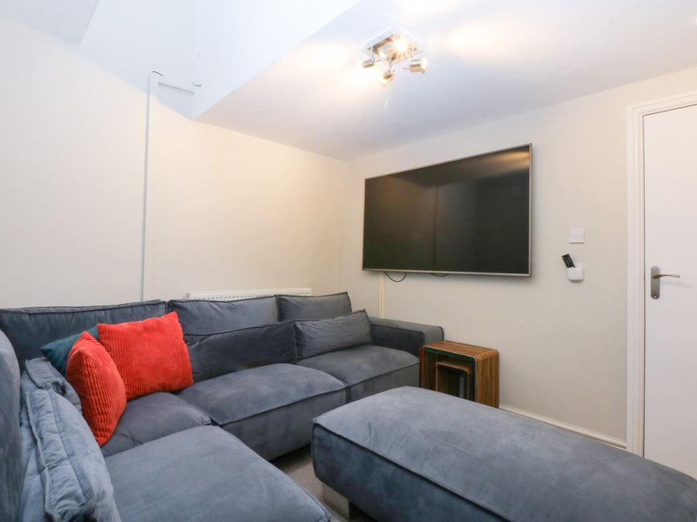 A living room with a sofa and television at Oak Cottage in Dinas Dinlle near Caernarfon