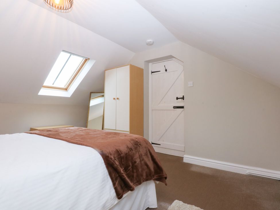 A bedroom with a bed and a wardrobe at Oak Cottage in Dinas Dinlle near Caernarfon
