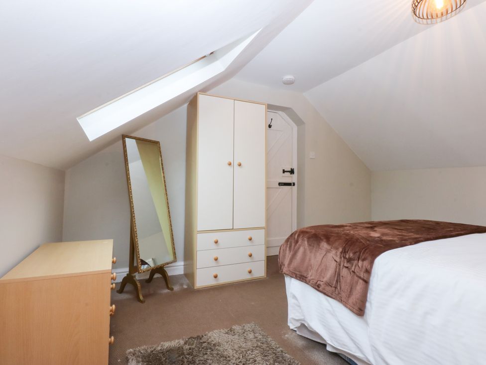 A bedroom with a bed and wardrobe at Oak Cottage Dinas Dinlle near Caernarfon