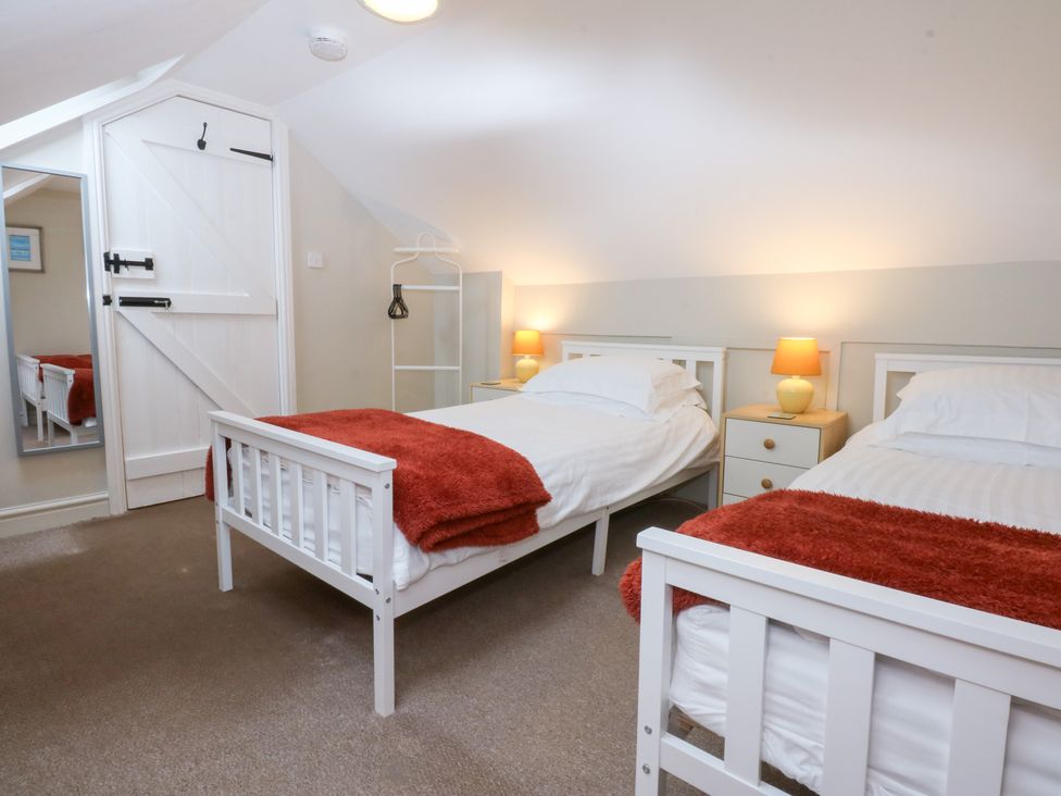 A bedroom with two beds and a dressing table at Oak Cottage in Dinas Dinlle near Caernarfon