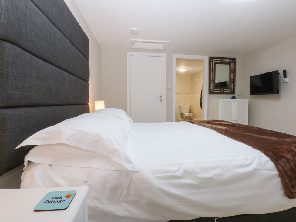 A bedroom with a bed and a television at Oak Cottage Dinas Dinlle near Caernarfon