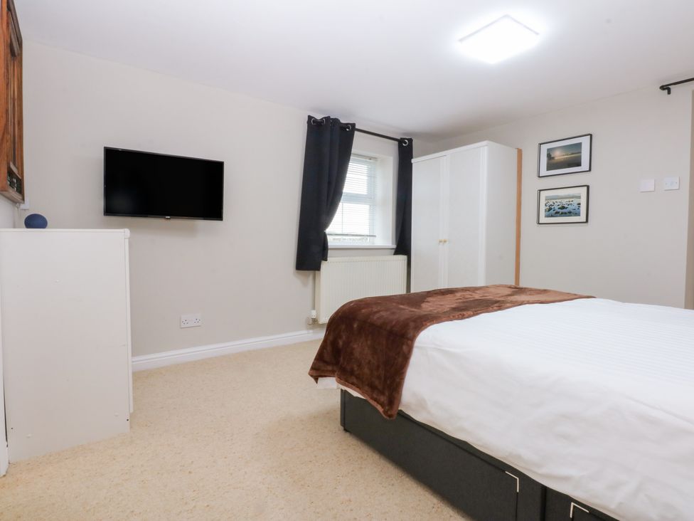 A bedroom with a bed and wardrobe at Oak Cottage Dinas Dinlle near Caernarfon