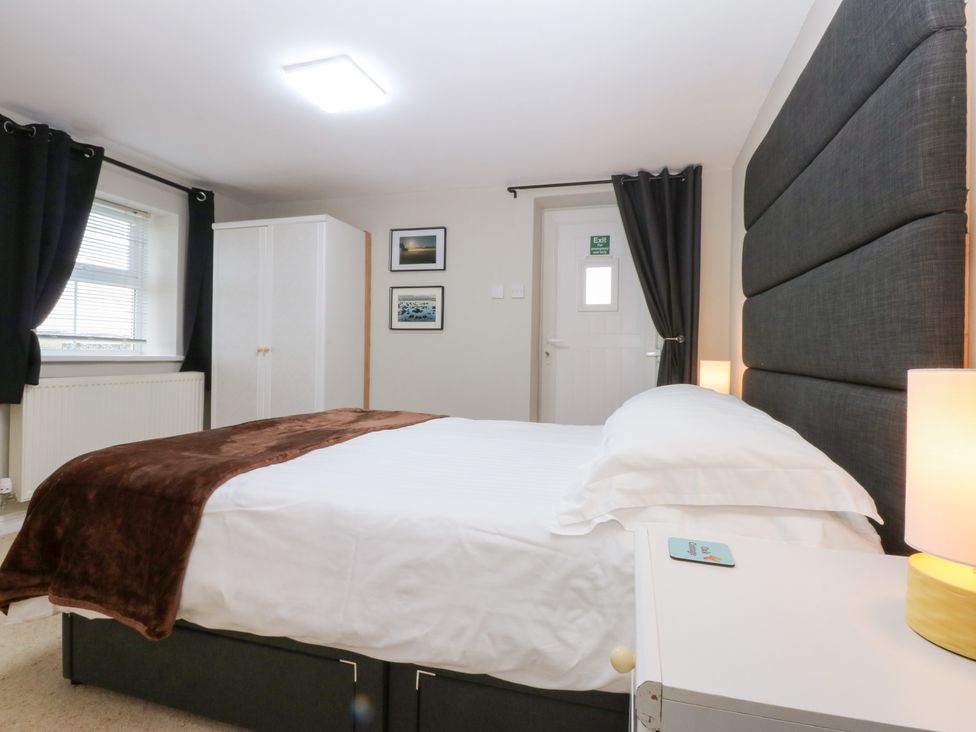 A bedroom with a bed and wardrobe at Oak Cottage in Dinas Dinlle near Caernarfon