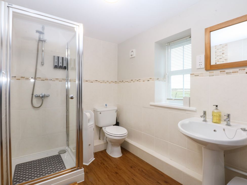 A bathroom with a shower, toilet and sink at Oak Cottage Dinas Dinlle near Caernarfon