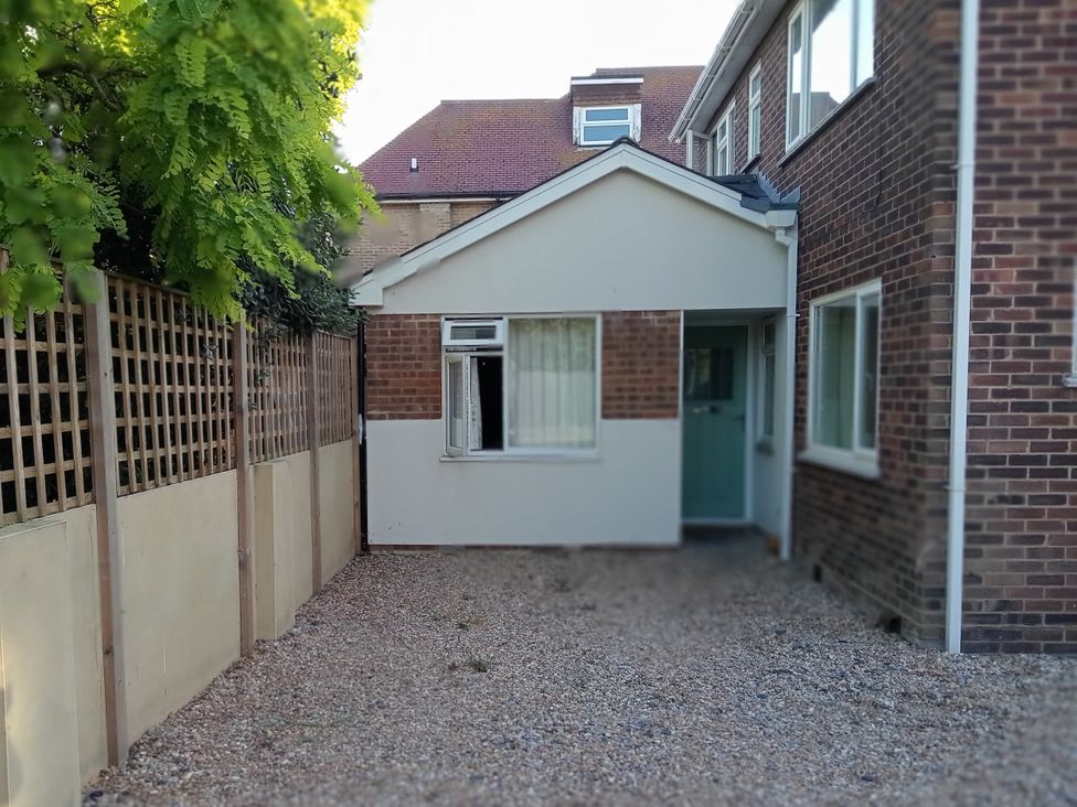 An outdoor area with house, fence, and gravel at The Garden House Cottage Whitstable
