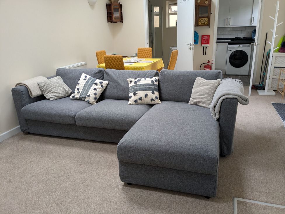A living room with a grey sofa and dining area at The Garden House Cottage in Whitstable
