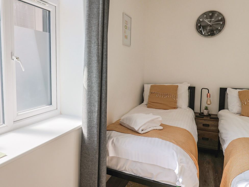 A bedroom with two single beds and a window at Lyme Zest in Lyme Regis