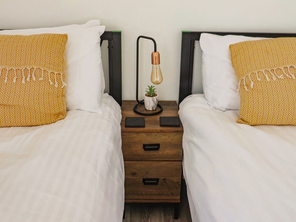 A bedroom with two beds and a nightstand at Lyme Zest in Lyme Regis
