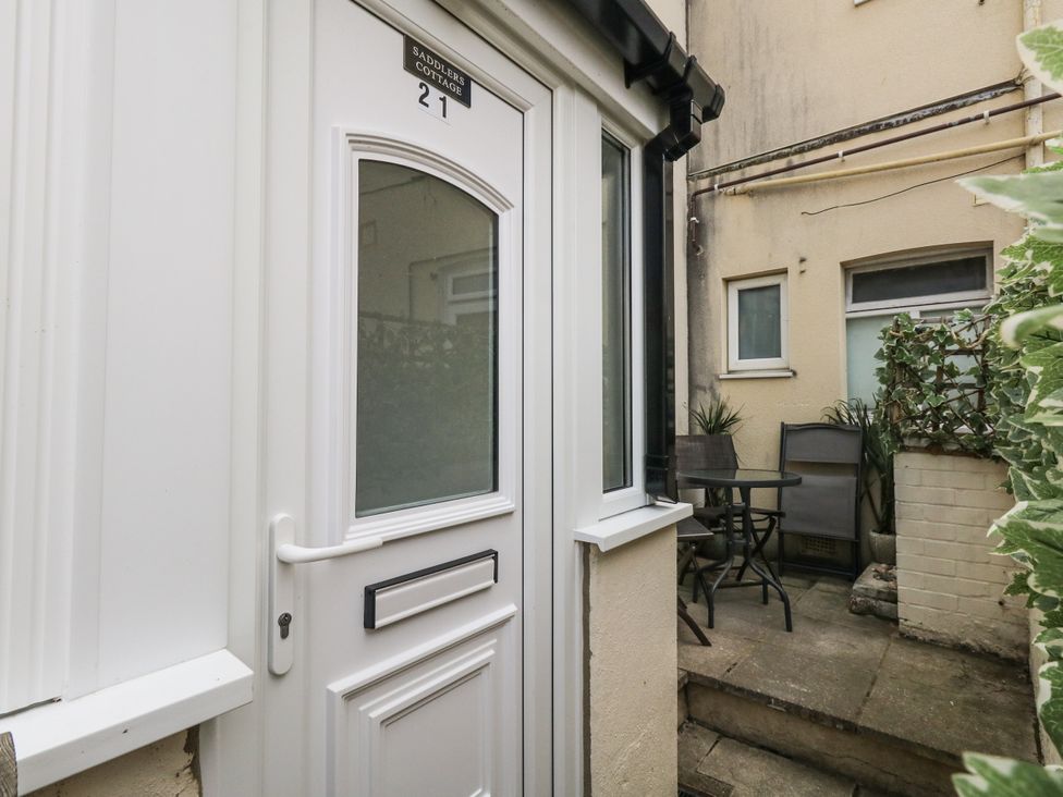 A door leading to a patio area with a table and chairs at Saddlers Cottage in Weymouth