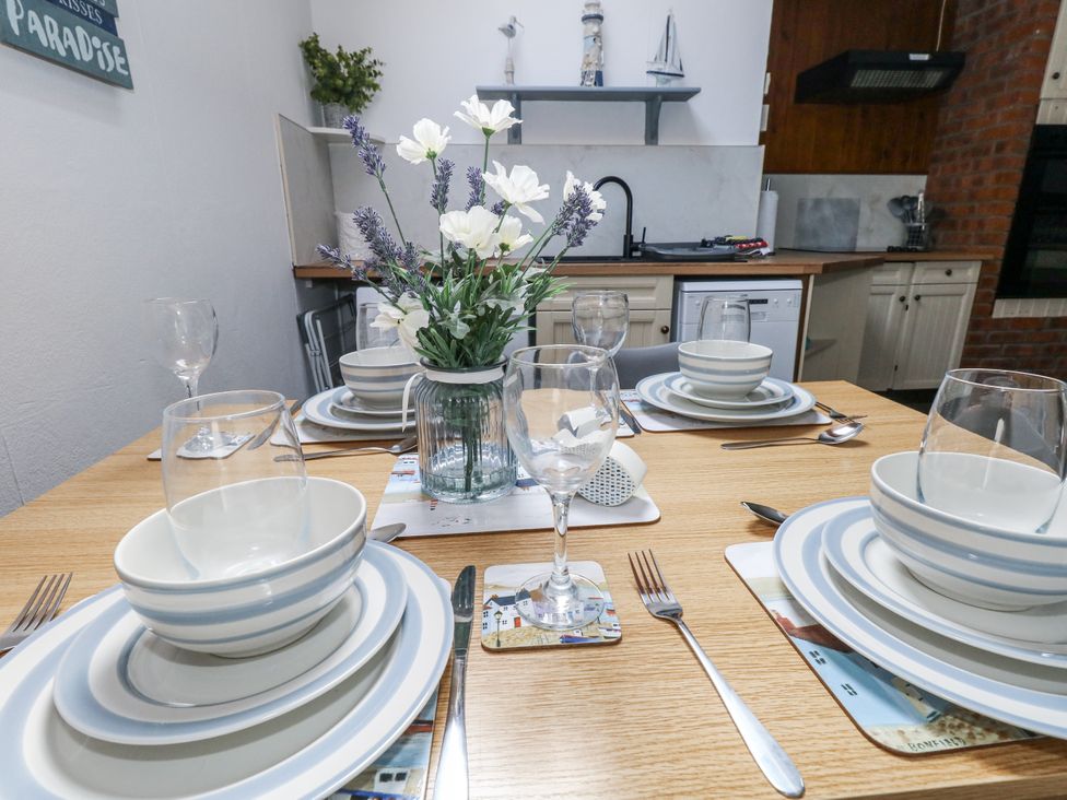 A dining table set with plates and glasses at Saddlers Cottage in Weymouth