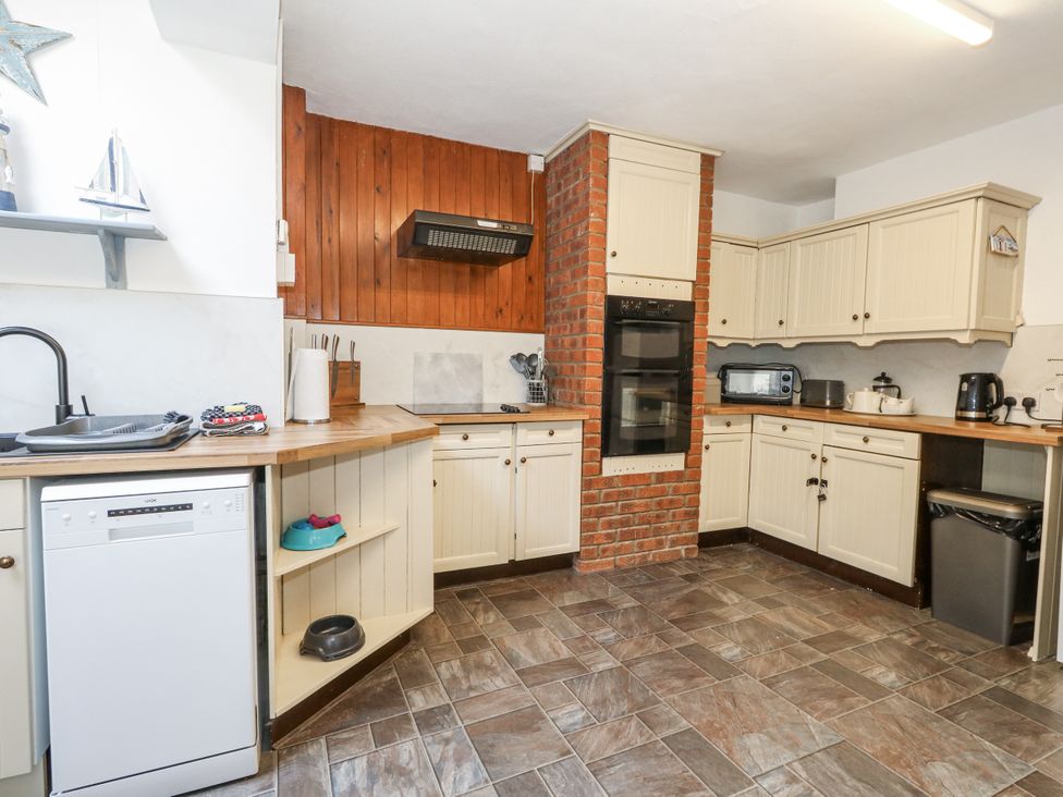 A kitchen with wooden countertop and appliances at Saddlers Cottage in Weymouth