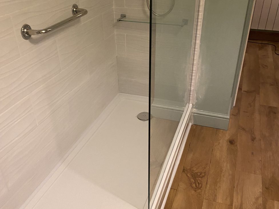 A shower enclosure with glass panel and drain at Seaspray in St Bees