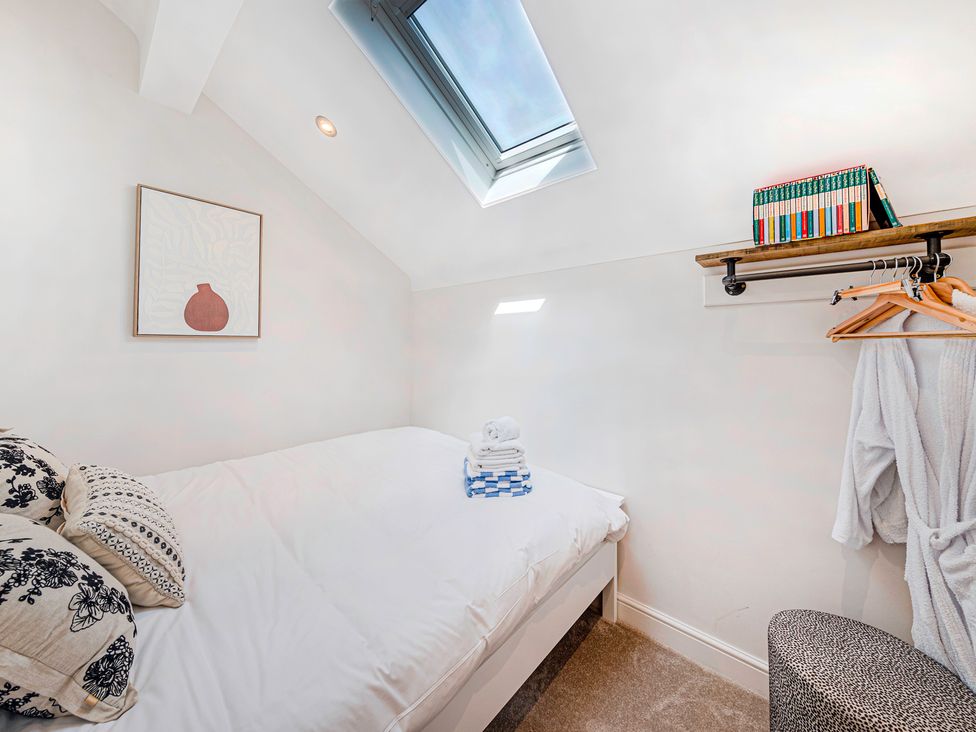 A bedroom with a bed, shelves of books, and a skylight at Fairvale House