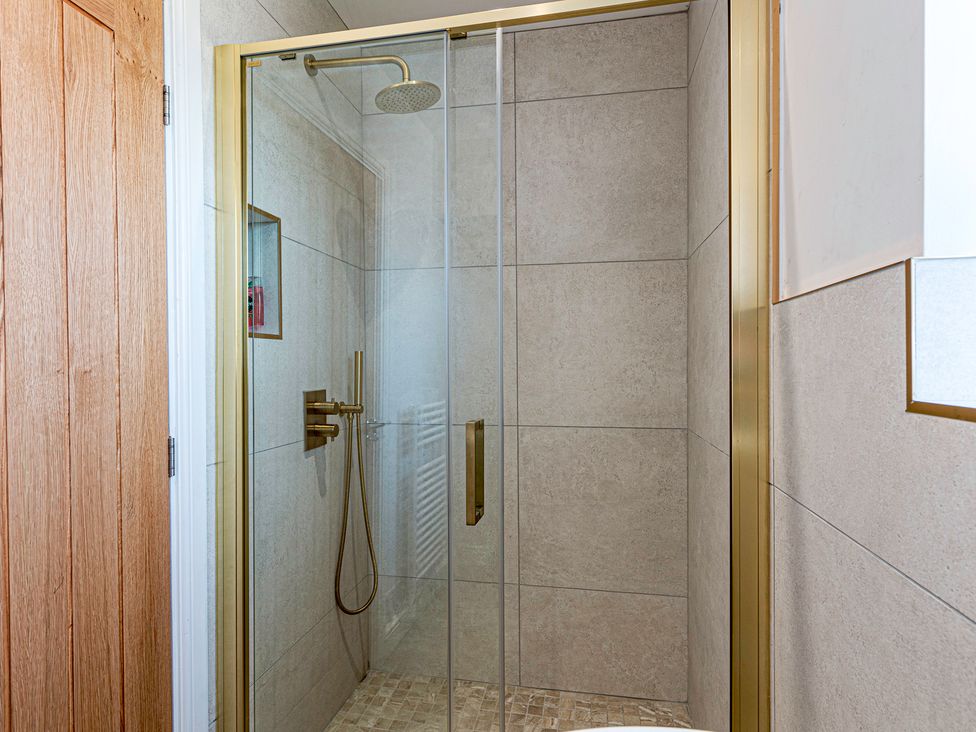 A shower enclosure with glass doors and tiled wall at Fairvale House