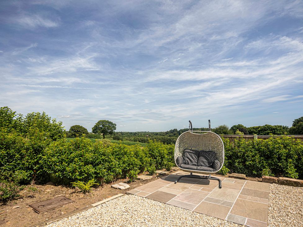 A hanging chair on a paved area surrounded by bushes at Fairvale House