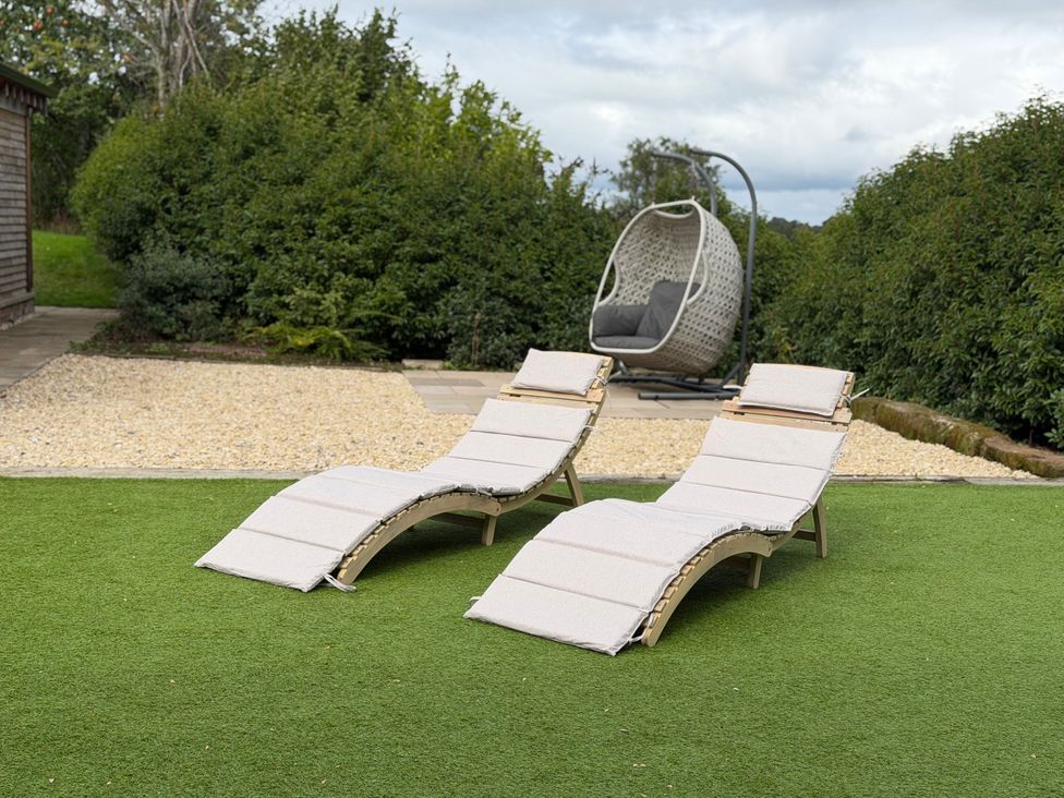 Two deck chairs and a hanging chair in the garden at Fairvale House in Northwich
