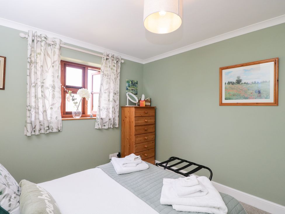 A bedroom with a bed and dresser at The Old Byre in Woodfalls