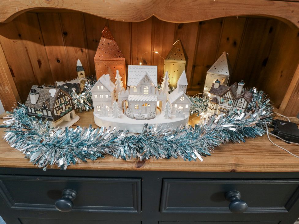 A display of decorative houses with lights and tinsel in the living room at The Old Byre in Woodfalls