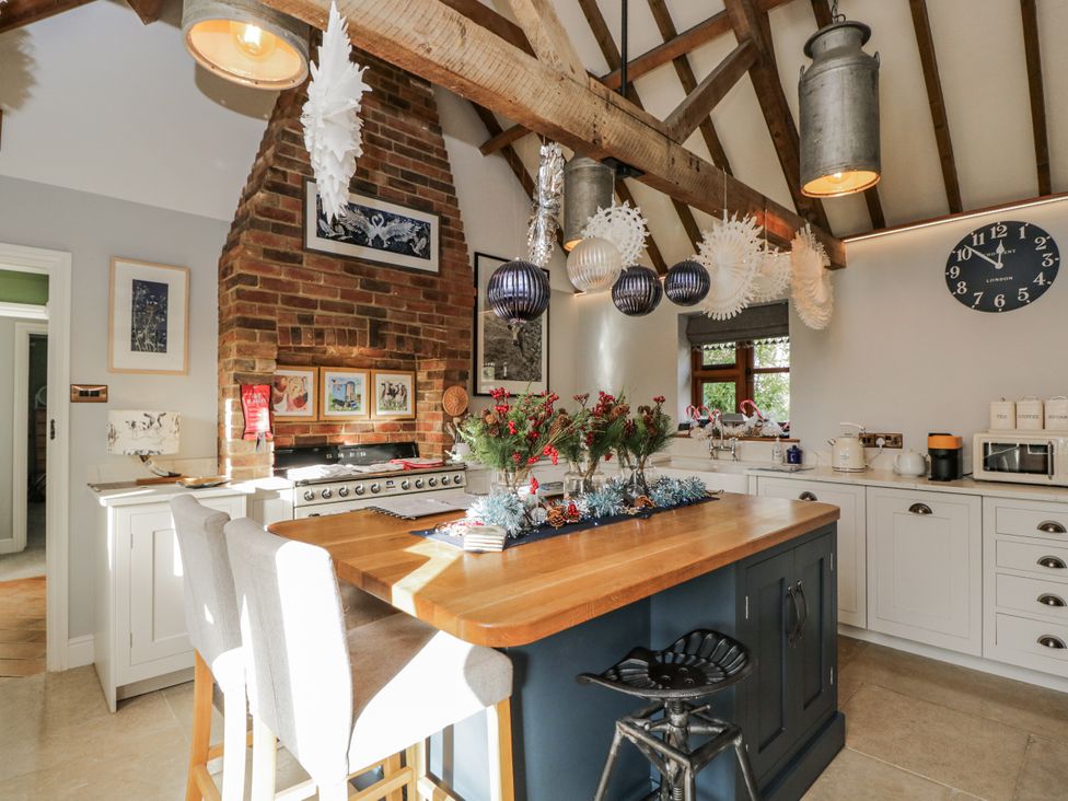 A kitchen with an island, stools, and a brick wall at The Old Byre in Woodfalls