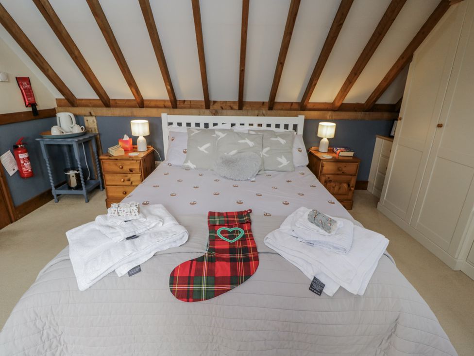A bedroom with a bed, towels, and a stocking at The Old Byre in Woodfalls