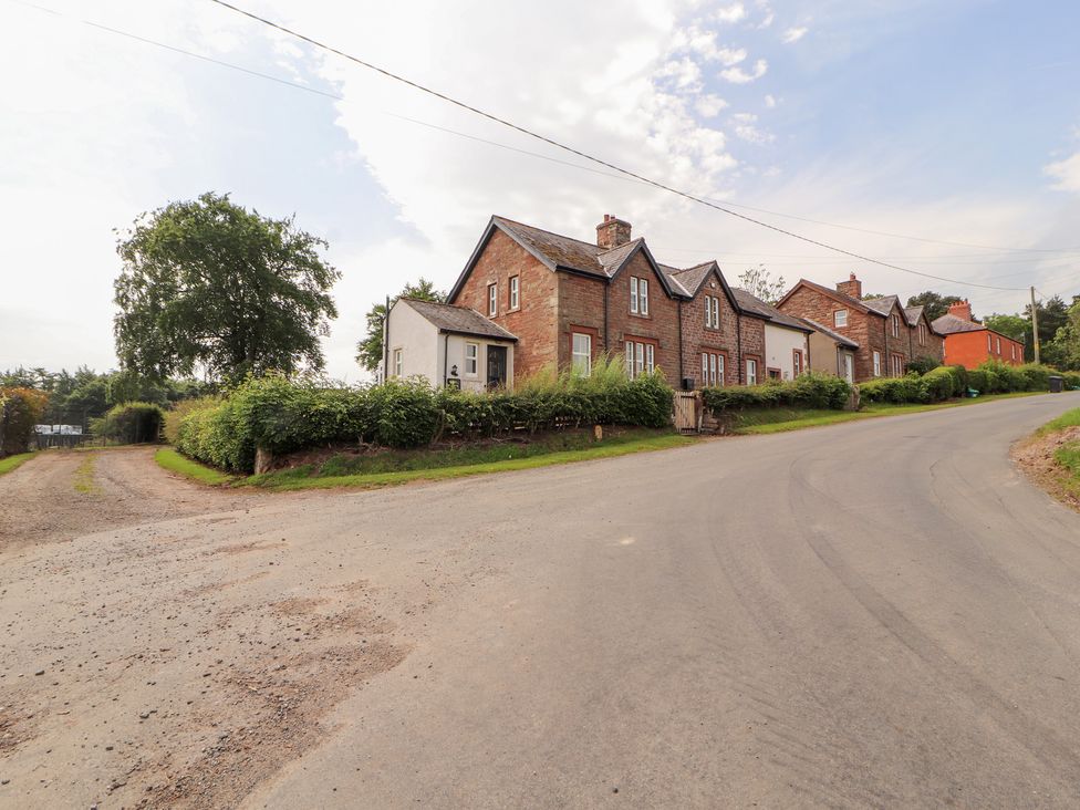 Houses along a road with green grass and trees at Rose Bank Cottage Dalston