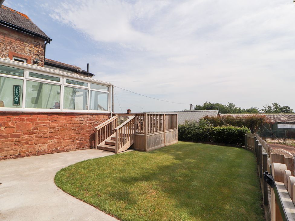 A garden with grass and decking at Rose Bank Cottage in Dalston