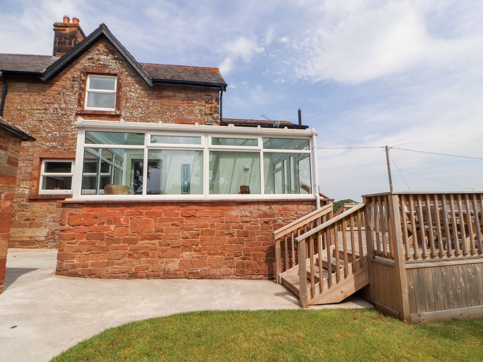A conservatory with stone wall and steps at Rose Bank Cottage in Dalston