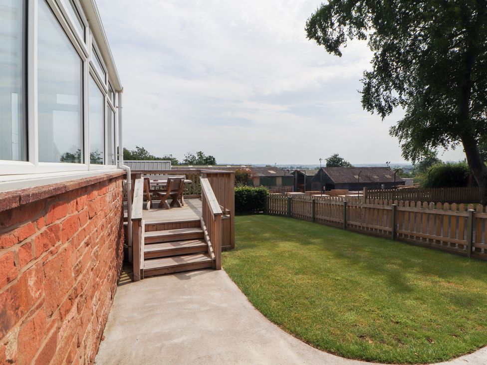 A garden with a deck and furniture at Rose Bank Cottage in Dalston