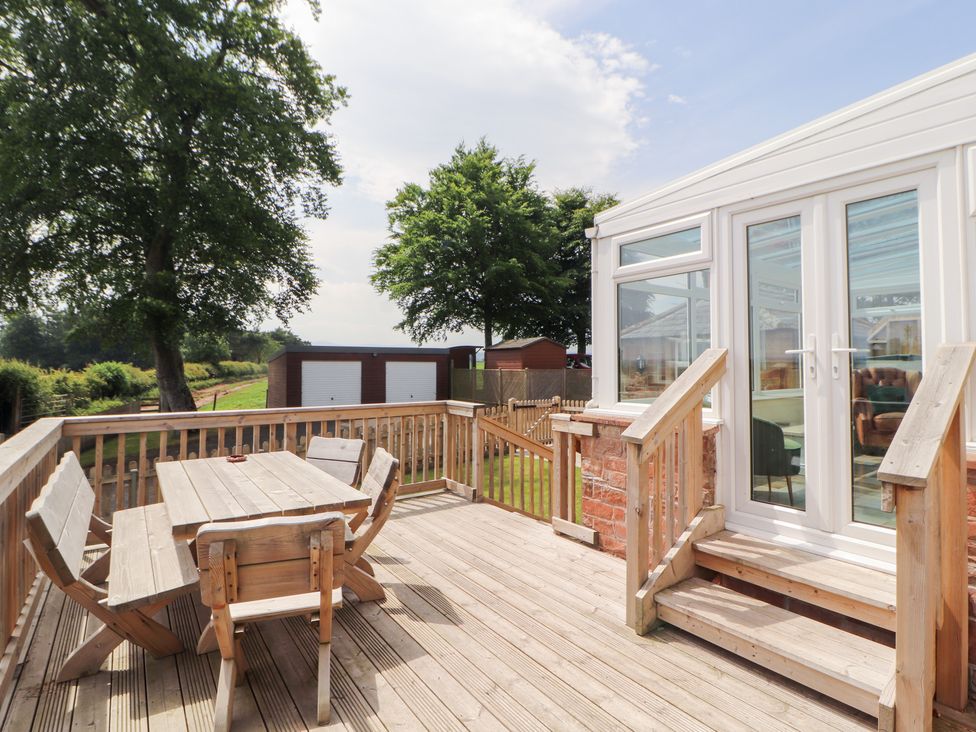 A deck with a wooden table and chairs at Rose Bank Cottage in Dalston